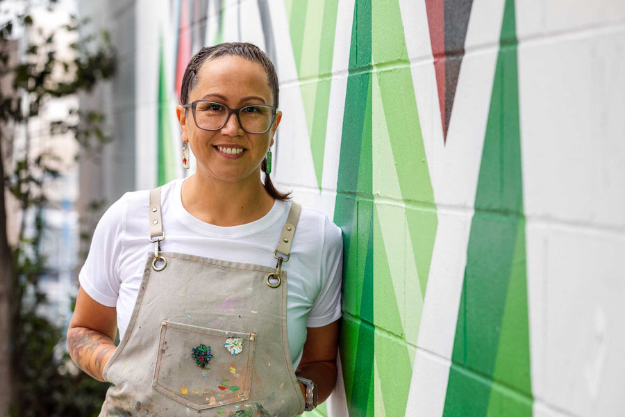 photo of artist Carrielynn Victor leaning against one of her murals