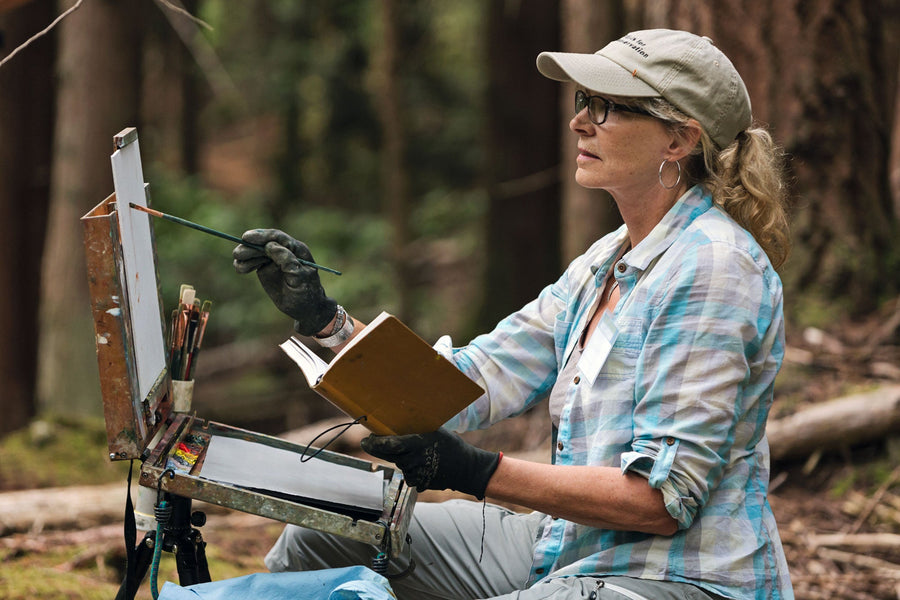 Artist Gaye Adams painting in the forest.