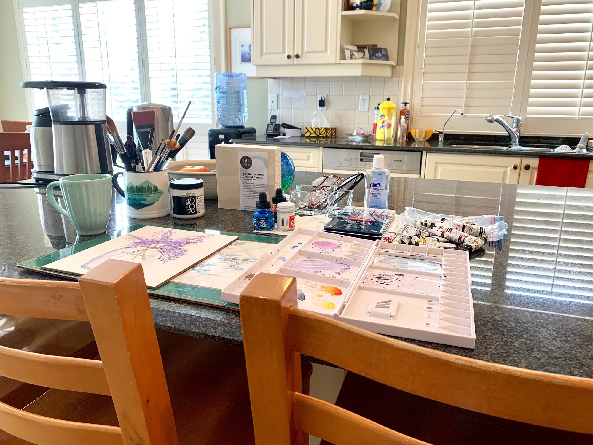 Barb Ferguson's kitchen counter transformed into a home art workspace with paints, brushes and palettes.
