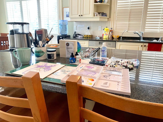 Barb Ferguson's kitchen counter transformed into a home art workspace with paints, brushes and palettes.