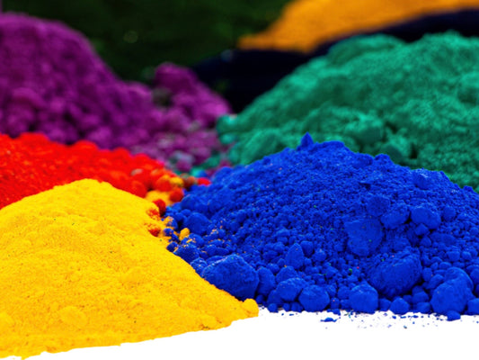A photo of 6 piles of colourful fine art pigments in red, purple, dark green, bright green, cobalt blue, and warm bright yellow