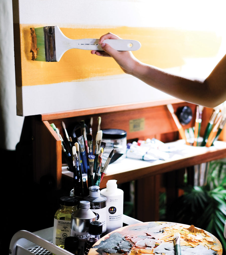 Close up image of an artist painting a canvas on an easel