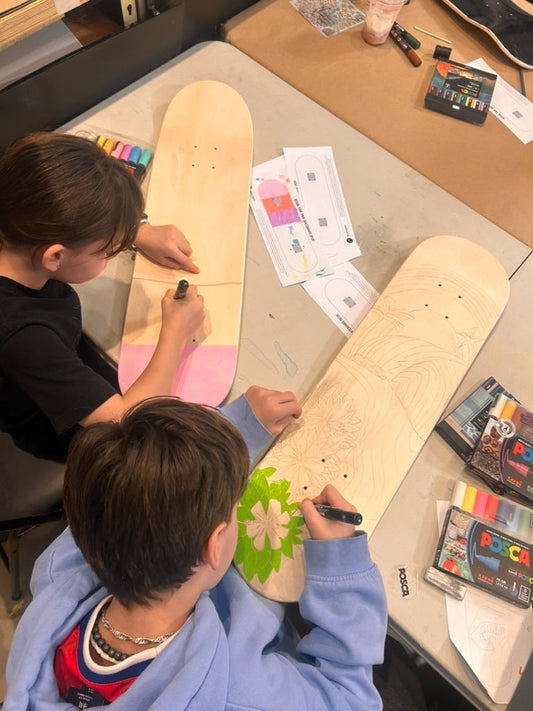 Two children customise  blank skateboard decks with acrylic markers