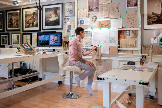 Artist Steve Chmilar sketching in his organised BC studio surrounded by artwork, materials and tools