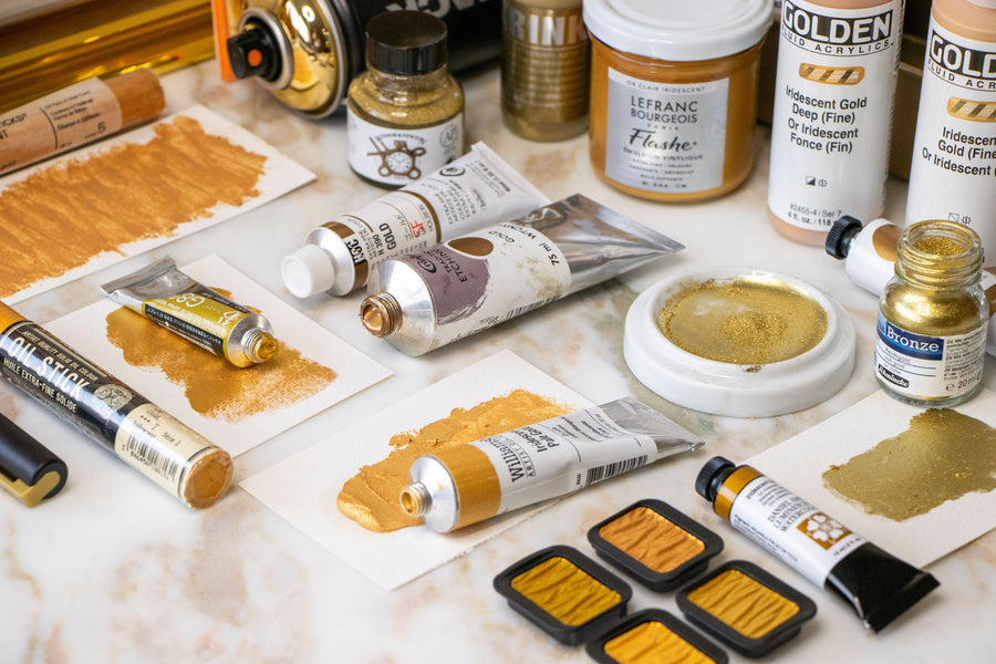 A selection of art materials in the colour Gold, including tubes and pans of paint, pigments, and pastels