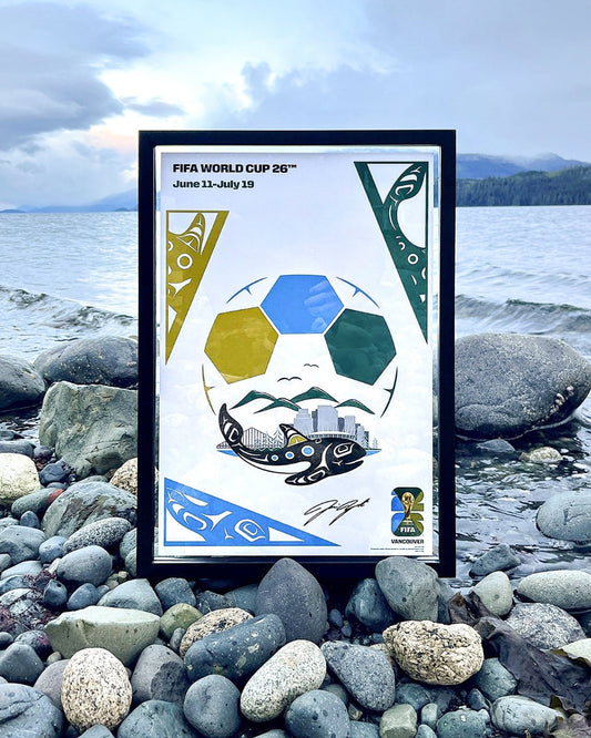 Artwork for the FIFA World Cup 26 Host City Poster by artist Jamin Zuroski  in a black frame on the rocks of a Vancouver BC beach.