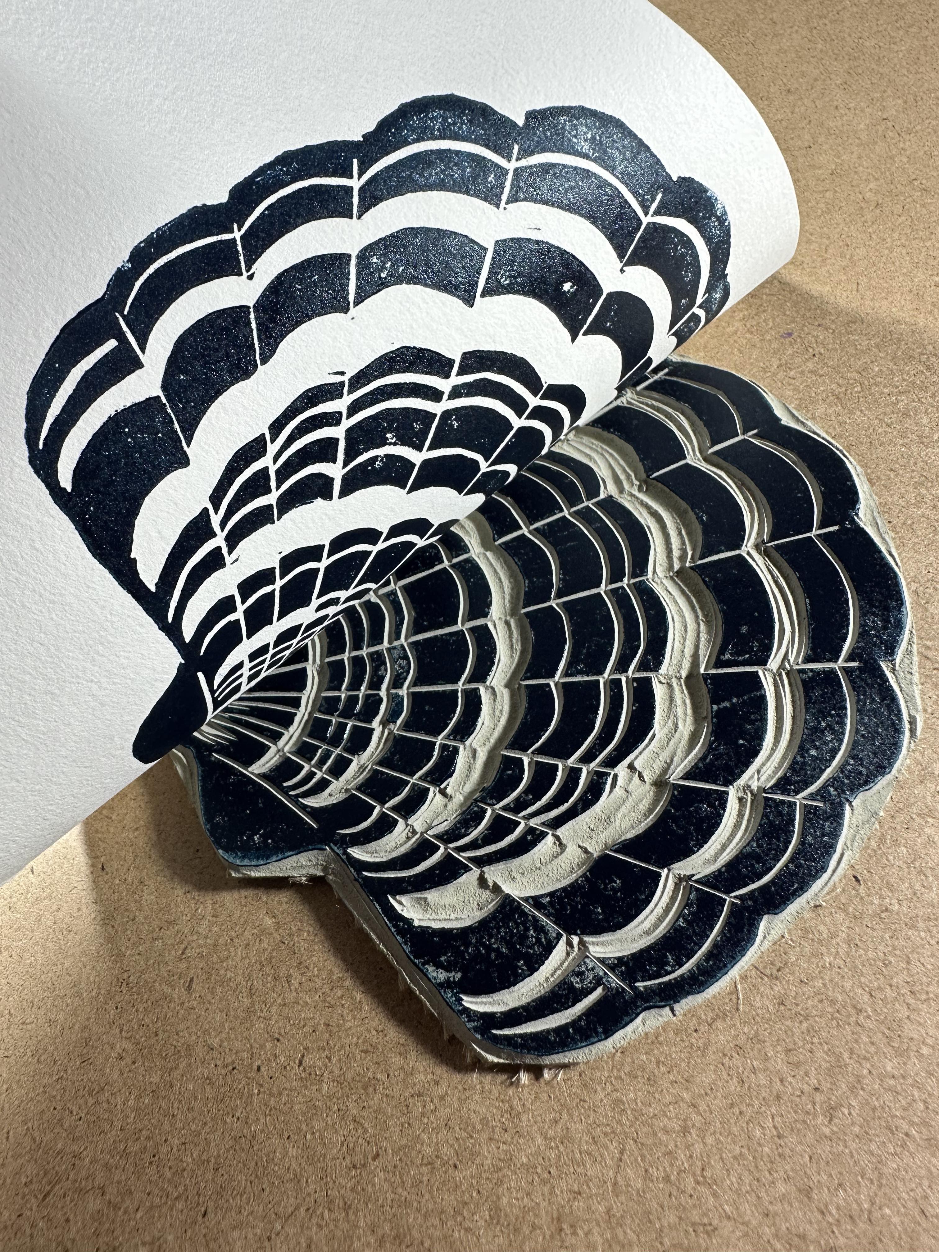 Peeling back printmaking paper to reveal the first seashell lino print.