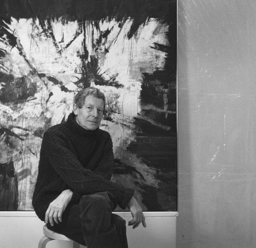 A black and white portrait of Gordon Smith with one of his abstract paintings