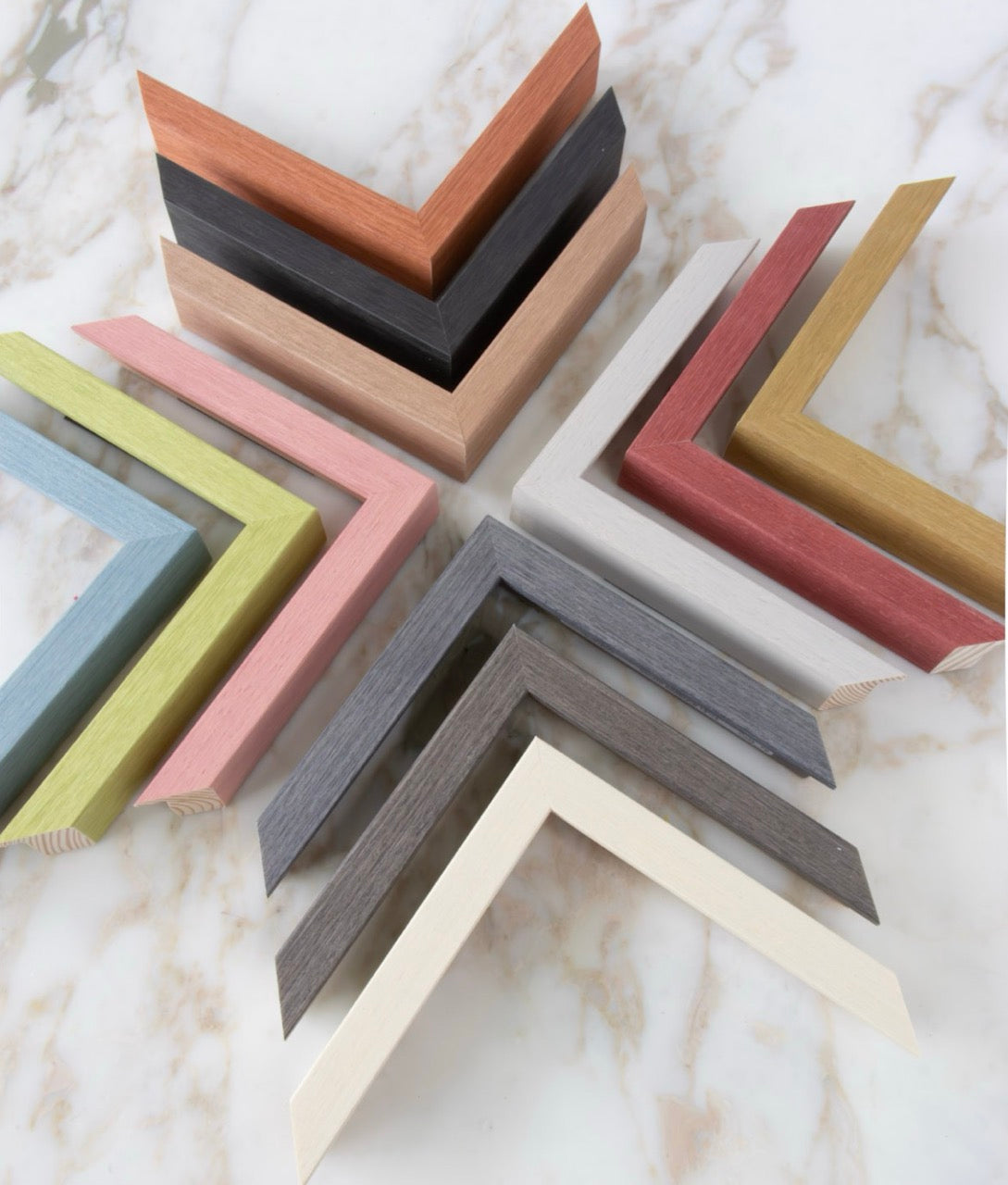 our new selection of frame mouldings from the Essence line, arranged into an 8 pointed star shape on a marble table top