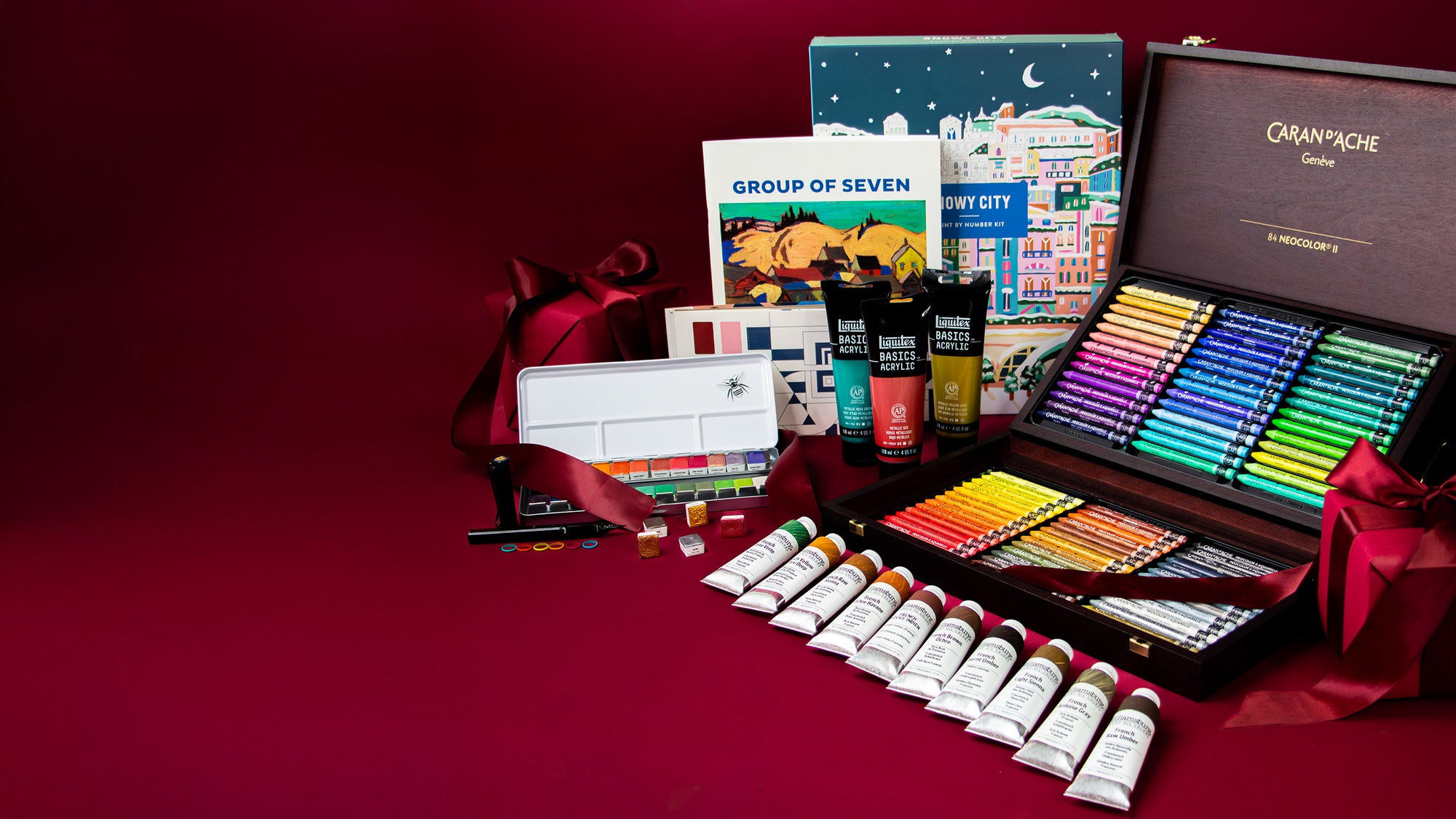 Art supplies including pastels, paint tubes, and books on a red background