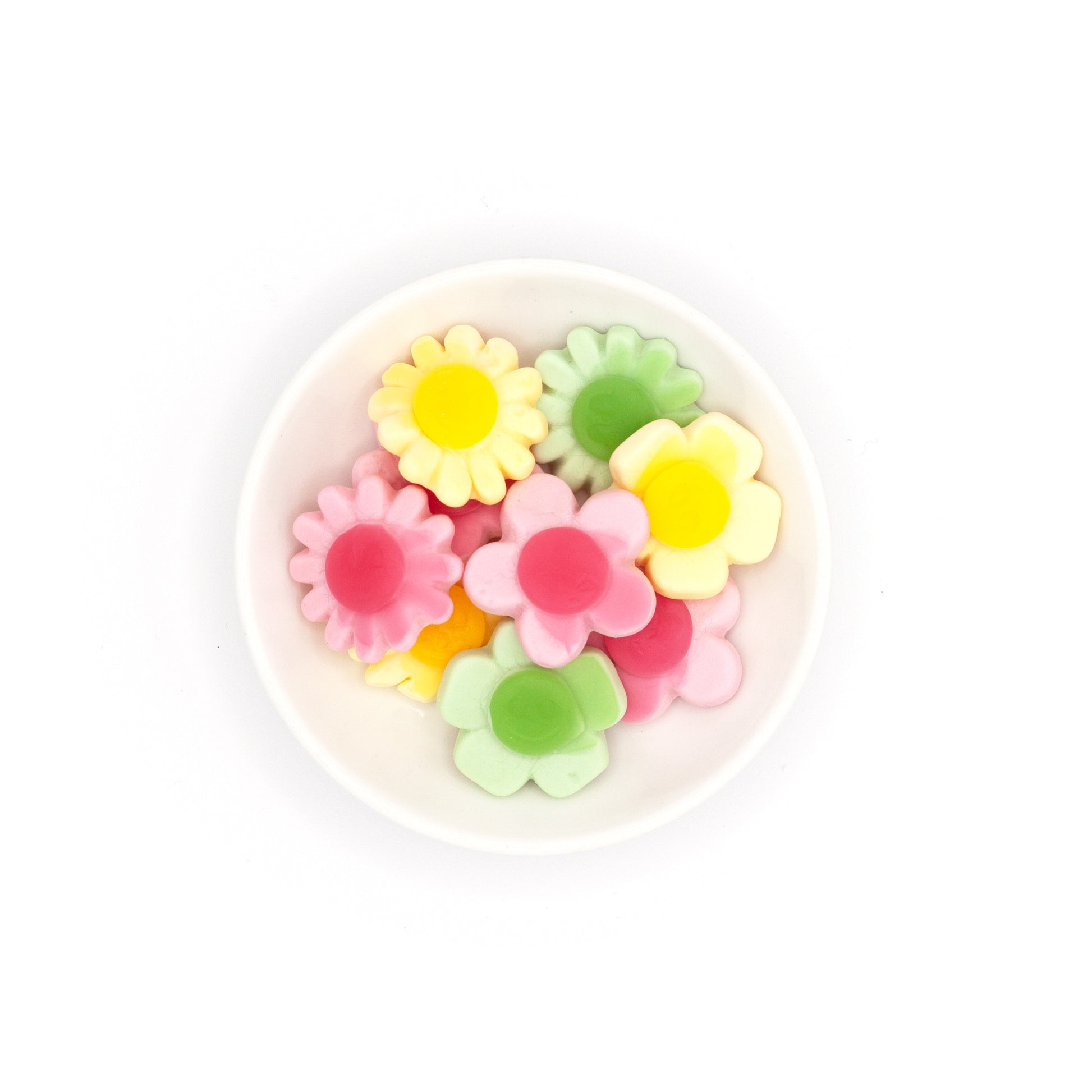 Colorful flower-shaped candies in a white container on a white background