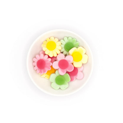 Colorful flower-shaped candies in a white container on a white background